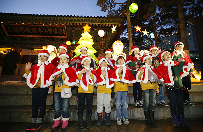 조계사 어린이합창단원들이 17일 조계사 일주문 앞을 밝힌 크리스마스트리 앞에서 “메리 크리스마스”를 외치며 손을 흔들고 있다. 