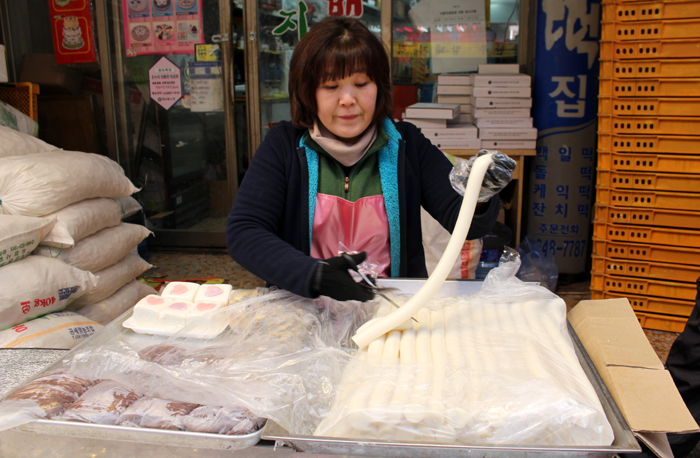 Una vendedora corta con una tijera un trozo de barra de garaetteok en una tienda en la que se elabora pastel de arroz, en el mercado de Mokdong, Yangcheon-gu, en la parte oeste de Seúl.