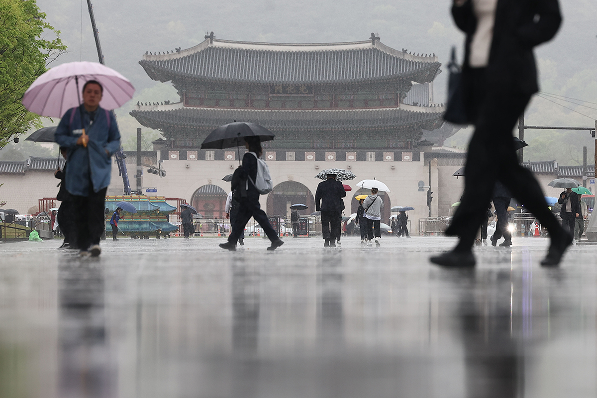 En la mañana del 15 de abril, los transeúntes caminan con paraguas por la plaza Gwanghwamun, ubicada en el distrito de Jongno-gu, en Seúl.