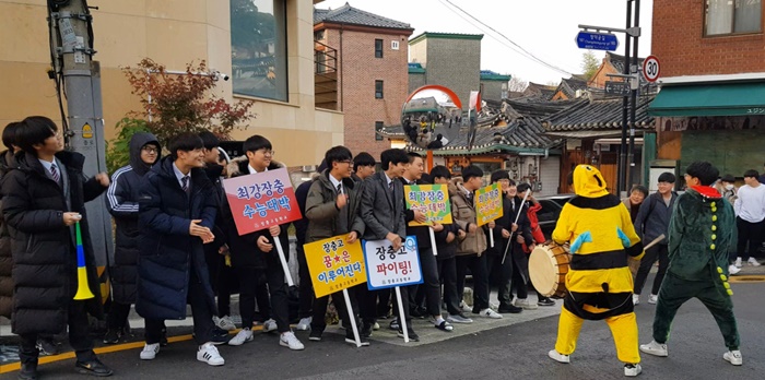 Unos estudiantes animan a sus compañeras de último año que se presentan al examen de ingreso a la universidad, frente de la Escuela Preparatoria Choong Ang, en el distrito de Jongno-gu, Seúl, el 15 de noviembre. | Kim Hyelin