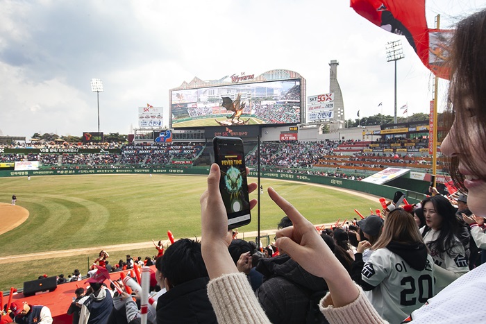Una modelo de SK Telecom explica el método de utilizar la aplicación móvil para hacerle volar al dragón en la realidad aumentada, el 23 de marzo en la inaguración de la Liga de la Organización Coreana de Béisbol (KBO, por sus siglas en inglés).