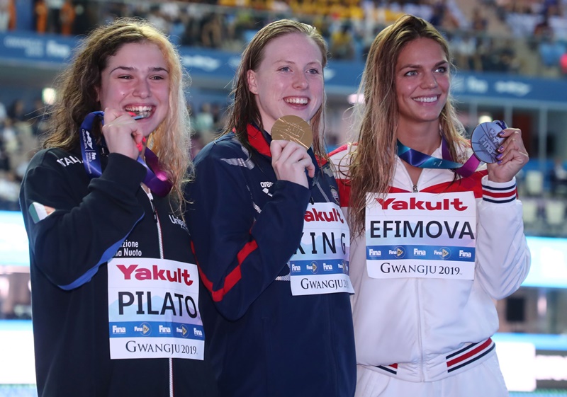 Lilly King (centro), campeona estadounidense de los 50m braza femenina, posa en la ceremonia de entrega de medallas, junto a la medallista de plata, Benedetta Pilato (izda.) de Italia y la ganadora de bronce, Yuliya Efimova (dcha.) de Rusia, el 28 de julio en el Centro Acuático Mundial de la Universidad de Nambu. | Comité Organizador del Campeonato Mundial de Natación 2019