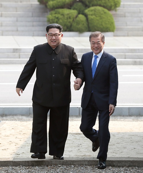 El presidente Moon Jae-in (dcha.) y el líder norcoreano Kim Jong Un cruzan, el 27 de abril, la Línea de Demarcación Militar (MDL, por sus siglas en inglés), la frontera intercoreana en la aldea de la tregua de Panmunjeom antes de celebrar su primera cumbre. | Equipo conjunto de prensa de la Cumbre Intercoreana 2018