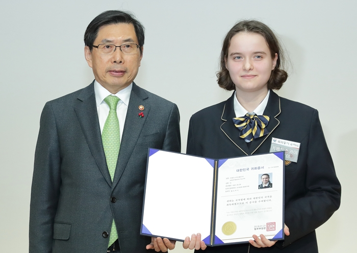 Kavetskya Yuliya (dcha.), originaria de la República de Belarús posa con el ministro mostrando su certificado de nacionalidad.