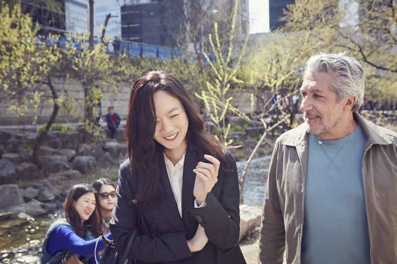 Los dos protagonistas de la película #Aquíestoy, Stephane y Soo pasean conversando por el arroyo Cheonggyecheon, en el centro de Seúl en una escena. 