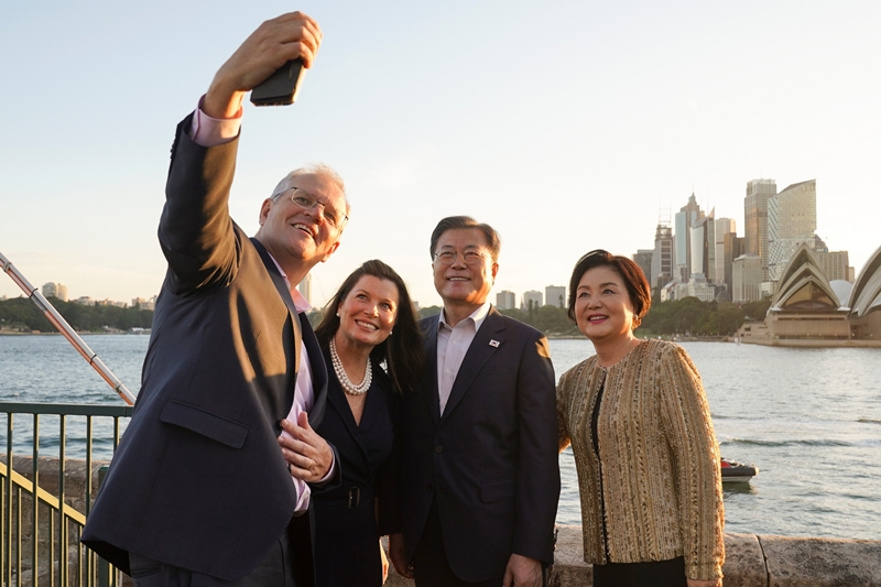  Antes de partir hacia Seúl desde Sídney, el 15 de diciembre el presidente Moon expresó sus impresiones de su viaje completo de cuatro días a Australia en sus redes sociales, diciendo que ambos países superarán la crisis del COVID-19, la crisis climática y las interrupciones de la cadena de suministro y liderarán un nuevo cambio. Al publicar una foto conmemorativa con el primer ministro australiano y su esposa frente a la Ópera de Sídney, el presidente dijo que su visita se realizó para aumentar la cooperación bilateral en las cadenas de suministro de minerales clave y elementos de tierras raras, así como en la industria de defensa. Los dos países compartirán tecnología de neutralidad de carbono, cooperarán en la economía del hidrógeno y buscarán el desarrollo en la industria espacial, agregó. | Página oficial de Facebook de Cheong Wa Dae 