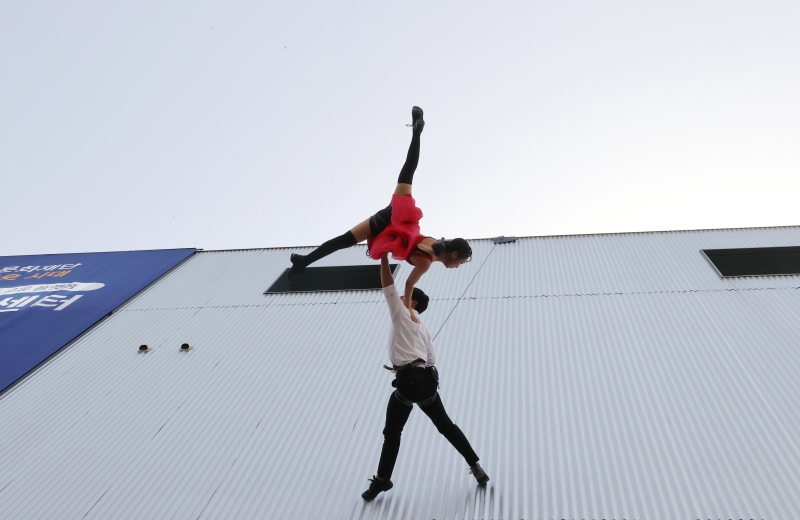 12일 오후 서울 종로구 서울연극센터에서 열린 재개관 기념행사에서 공중퍼포먼스 전문 단체 단디 소속 단원들이 로프에 몸을 묶고 건물 외벽에서 축하 퍼포먼스를 하고 있다. 