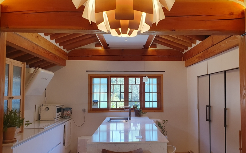 La cocina de 'Seoheejae' combina elementos tradicionales de un hanok, como el techo de tejas y las ventanas de estilo coreano, con elementos modernos como un fregadero y un refrigerador, creando así una armonía entre la tradición y la modernidad.