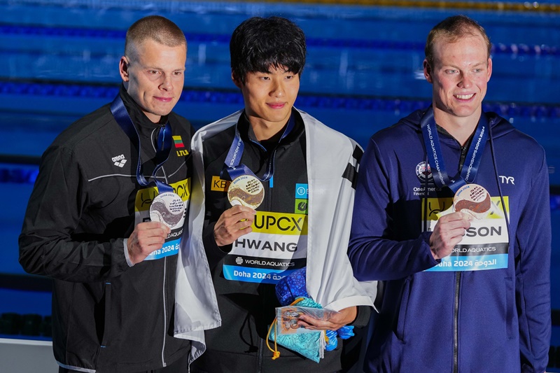 El nadador coreano Hwang Sun-woo (centro), ganador de la medalla de oro, posa junto al lituano Danas Rapsys (izquierda), ganador de la plata, y el estadounidense Luke Hobson, ganador del bronce, en la ceremonia de entrega de medallas de los 200 m estilo libre masculino en el Campeonato Mundial de Natación, el 13 de febrero (hora local), en el domo Aspire en Doha, Catar. | Agencia de Noticias Yonhap 