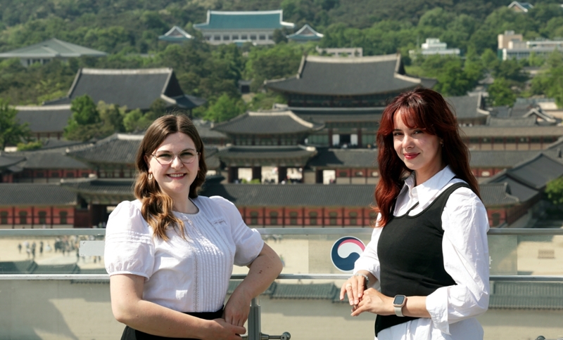 Anne Sophie Schroeder (izda.), de Alemania, y Sarah Shalaby, de Francia, dos voluntarias del Festival de Cultura Real de primavera de este año, posan para una foto el 10 de mayo con el palacio de Gyeongbokgung al fondo, en el distrito Jongno-gu de Seúl. | Jeon Han 