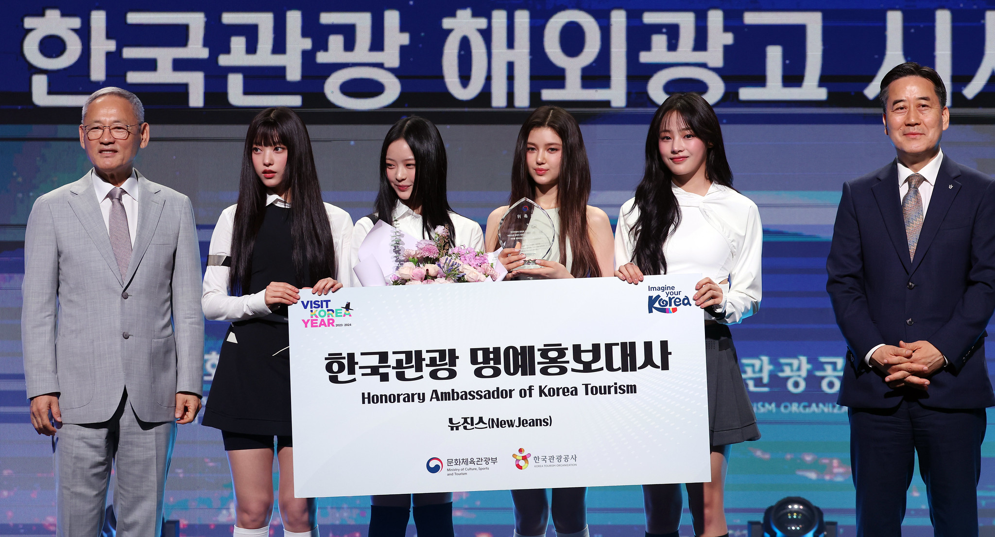El 11 de julio, el grupo femenino de K-pop NewJeans se toma una foto conmemorativa con el ministro de Cultura, Deportes y Turismo, Yu In Chon (primero desde la izquierda), y el presidente de la Organización de Turismo de Corea (KTO, por sus siglas en inglés), SEO Young Chung (primero desde la derecha), luego de ser nombrado como embajador promocional de Corea, en el Hotel Grand Hyatt, en el distrito de Yongsan-gu, en Seúl.