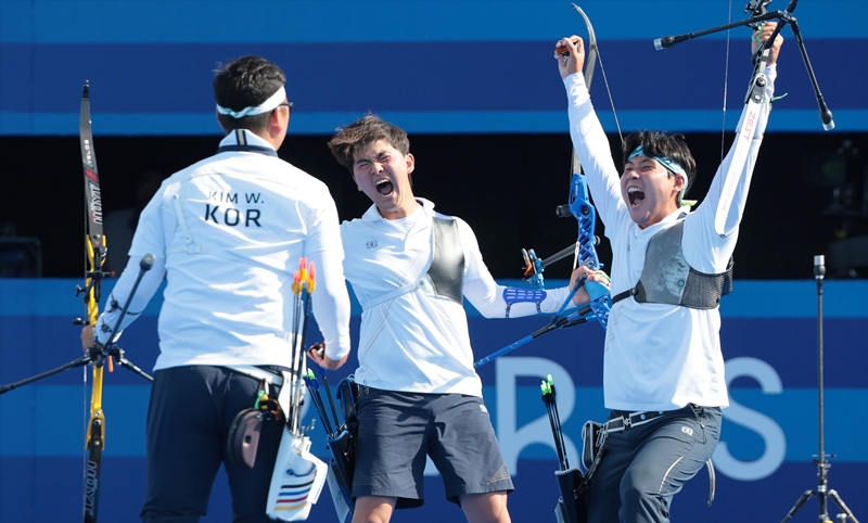 El 29 de julio (hora local), los arqueros coreanos Kim Woo-jin (izda.), Lee Woo-seok (dcha.) y Kim Je-deok (centro) celebran su victoria tras ganar el oro en la prueba de tiro con arco masculino por equipos de las Olimpiadas de París, en la Explanada de los Inválidos, en la capital francesa.