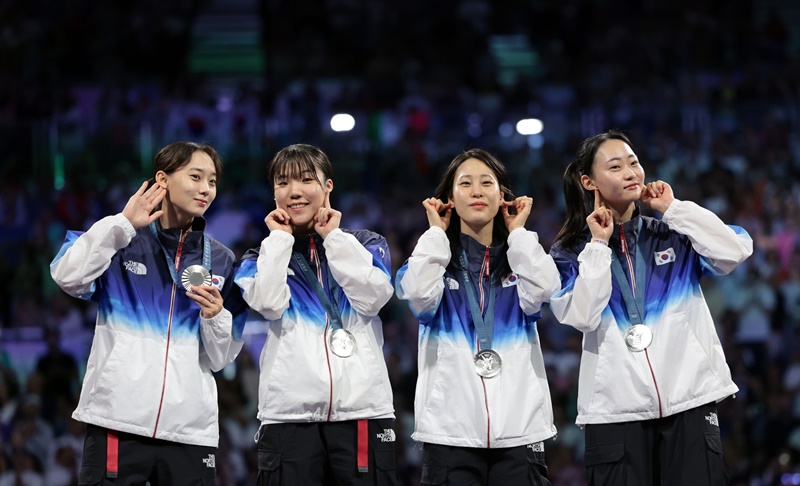 El equipo nacional femenino de esgrima, ganador de la medalla de plata (de izquierda a derecha), formado por Yoon Ji-soo, Jeon Ha-young, Jeon Eun-hye y Choi Se-bin, realiza el 4 de agosto (hora local), un gesto con los pendientes en la ceremonia de entrega de medallas de los Juegos Olímpicos de París 2024, celebrada en el Grand Palais. Los pendientes de cada jugadora representan uno de los cuatro trigramas de las esquinas de la bandera nacional coreana.