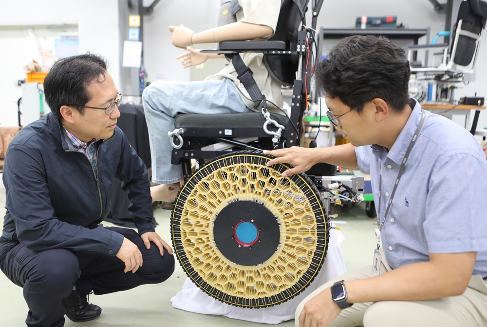 Song Sung-Hyuk (derecha), investigador principal del Centro de Robótica Avanzada del Instituto Coreano de Maquinaria y Materiales, y el director del centro, Kim Dong Il, inspeccionan una silla de ruedas equipada con las ruedas morfológicas que ellos inventaron.