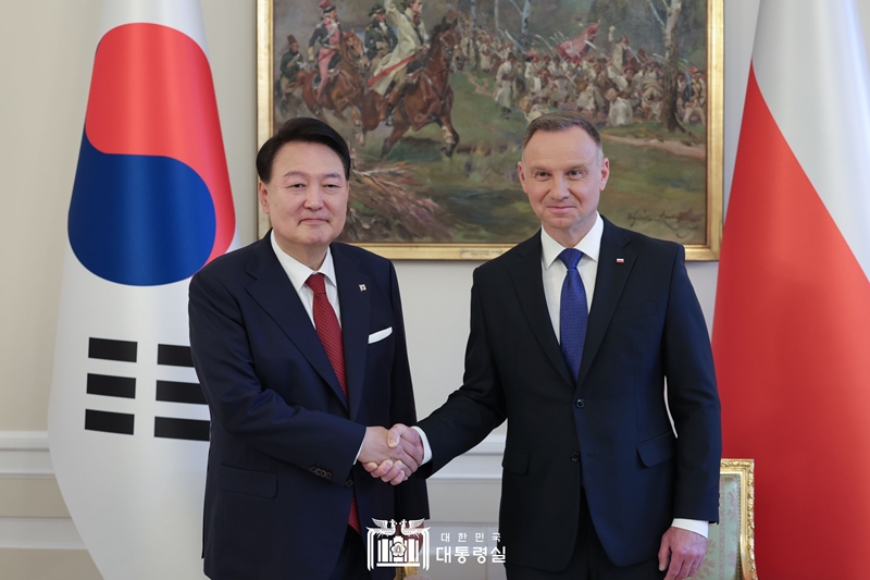 La foto, tomada el 13 de junio de 2023, muestra al preisdente Yoon Suk Yeol (izda.) y al presidente polaco Andrzej Duda dándose la mano antes de celebrar una cumbre. | Oficina presidencial 