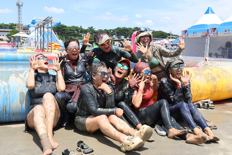 Los veraneantes en la playa de Daecheon levantan los brazos y gritan con entusiasmo durante el Festival del Barro de Boryeong.