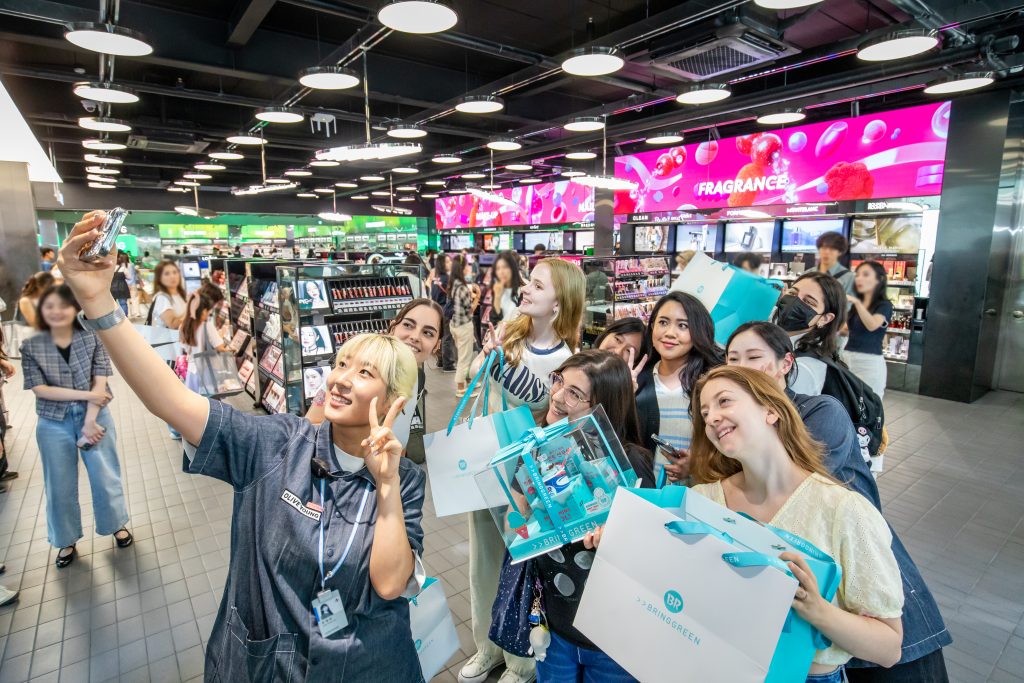 Un grupo de turistas extranjeros se toma una selfie frente a la sucursal de Myeong-dong de Olive Young, franquicia de productos de salud y belleza, en el distrito de Jung-gu, Seúl, en junio del año pasado. | CJ Olive Young