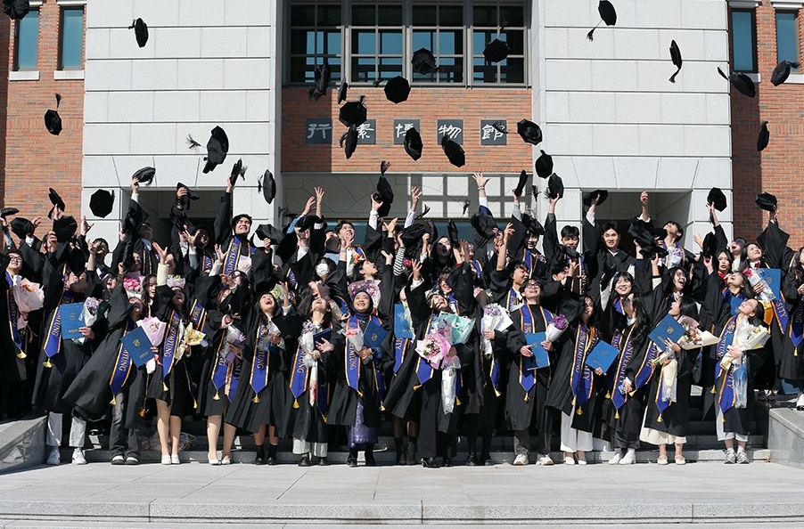 Unos estudiantes extranjeros de la Universidad de Keimyung lanzan sus birretes al aire durante su ceremonia de graduación, celebrada el 17 de febrero en el campus de Dalseo-gu, Daegu. | Universidad de Keimyung