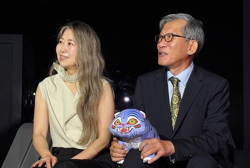 La creadora y codirectora de 'Las guerreras K-pop', Maggie Kang (izda.), observa el arte digital inmersivo, el 21 de agosto, en la Galería Digital del Museo Nacional de Corea, en Seúl, junto con el director general del museo, You Hong-june. | Charles Audouin