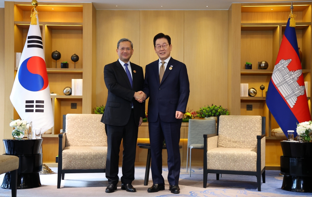 El presidente Lee Jae Myung (derecha) y el primer ministro camboyano Hun Manet se dan la mano antes de su cumbre bilateral, el 27 de octubre, en un hotel de Kuala Lumpur, Malasia.