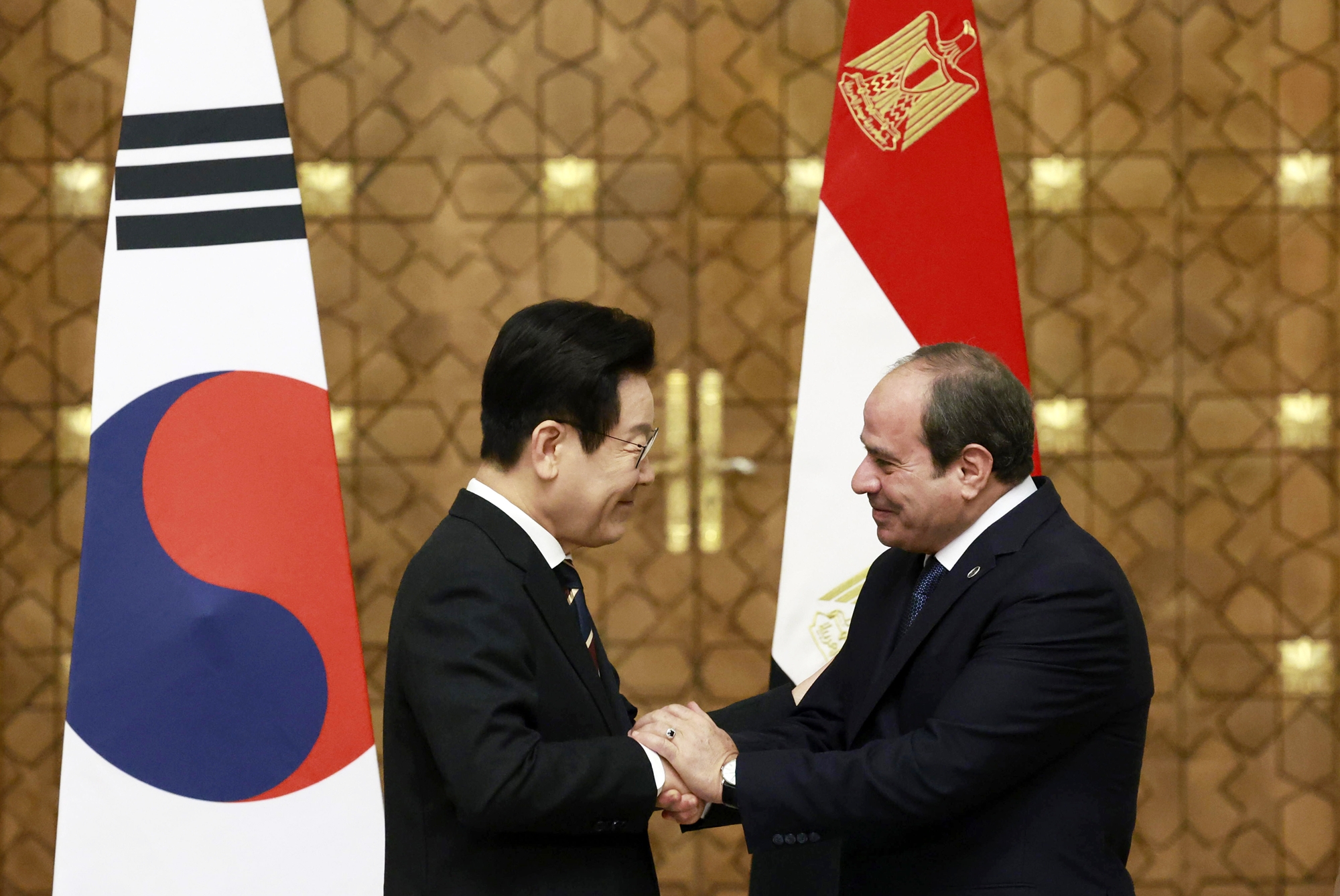 El presidente Lee Jae Myung (izda.) y su homólogo egipcio, Abdulfatah al-Sisi, se toman de la mano durante una confrencia de prensa conjunta tras sus diálogos cumbre, el 20 de noviembre (hora local), en el palacio presidencial de El Cairo, en Egipto. | Agencia de Noticias Yonhap