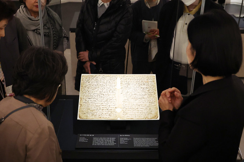 Los visitantes observan un bífolio del Corán, uno de los manuscritos más antiguos conservados del libro sagrado del islam, durante la vista previa para medios celebrada el 21 de noviembre en la recién inaugurada Galería de Arte Islámico del Museo Nacional de Corea. El manuscrito, datado entre finales del siglo VII y comienzos del VIII, constituye un recurso crucial para comprender la caligrafía y las técnicas de encuadernación previas al desarrollo de la tradición manuscrita islámica.