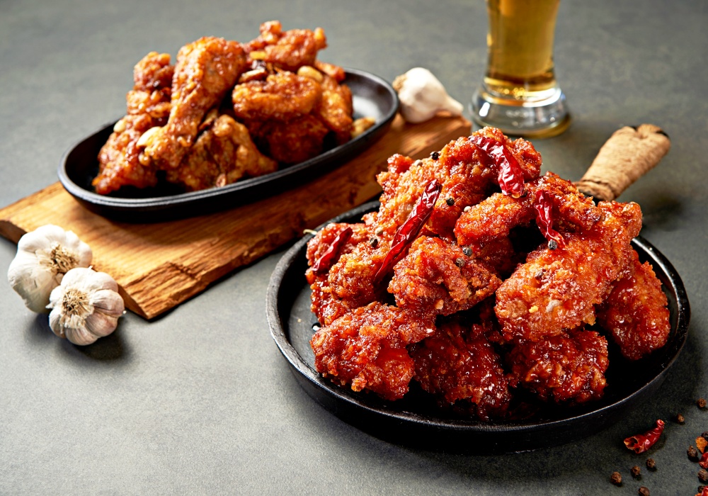 Pollo frito coreano aderezado con ajo y chile rojo. | iclickart (La reproducción o redistribución no autorizada de esta imagen está prohibida de acuerdo con las leyes de derechos de autor.)