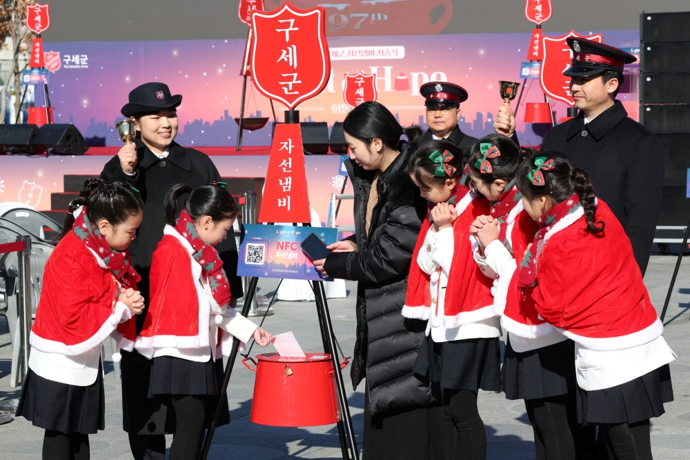 Unos ni&ntilde;os depositan donaciones en un caldero del Ej&eacute;rcito de Salvaci&oacute;n de Corea, el 28 de noviembre, en el barrio de Myeong-dong, en el distrito de Jung-gu, en Se&uacute;l.