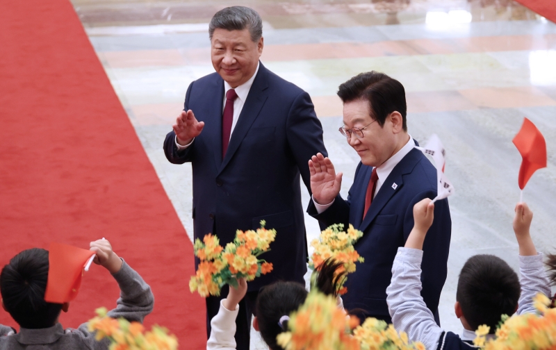 El presidente Lee Jae Myung (derecha) y el presidente chino Xi Jinping saludan a niños que asisten a la ceremonia oficial de bienvenida celebrada el 5 de enero en el Gran Palacio del Pueblo, en Pekín. | Agencia de Noticias Yonhap
