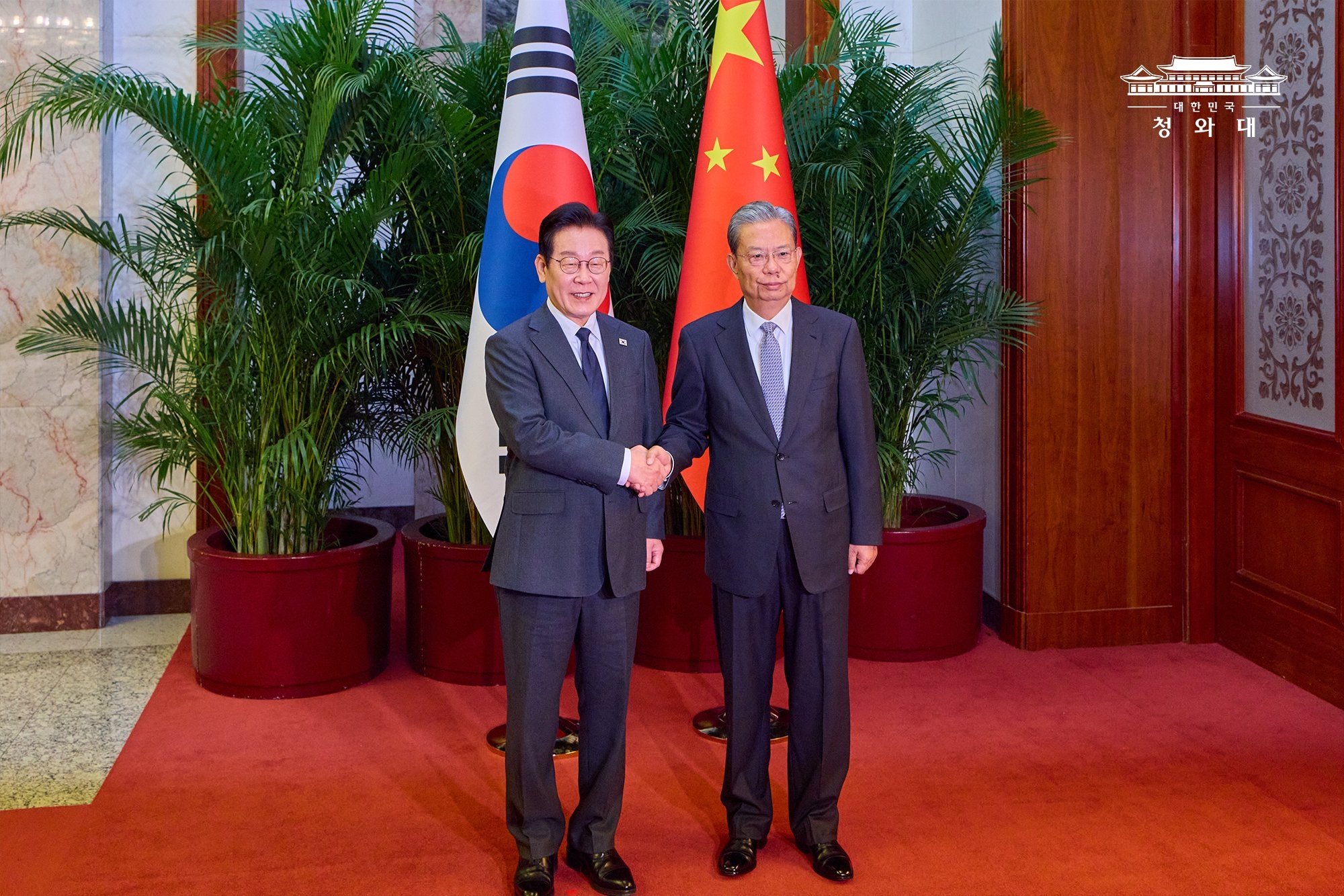 El presidente Lee Jae Myung (izquierda) se toma una fotografía con Zhao Leji, presidente del Comité Permanente de la Asamblea Popular Nacional, el 6 de enero, en el Gran Salón del Pueblo, en Pekín.