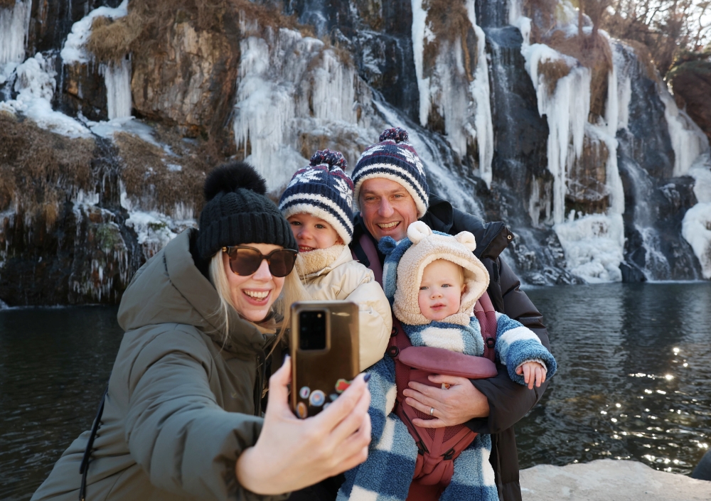 La foto, tomada el 7 de enero de 2026, muestra a unos turistas extranjeros tomándose una foto frente a la cascada de Hongje en el distrito de Seodaemun-gu, Seúl. | Lee Jeong Woo