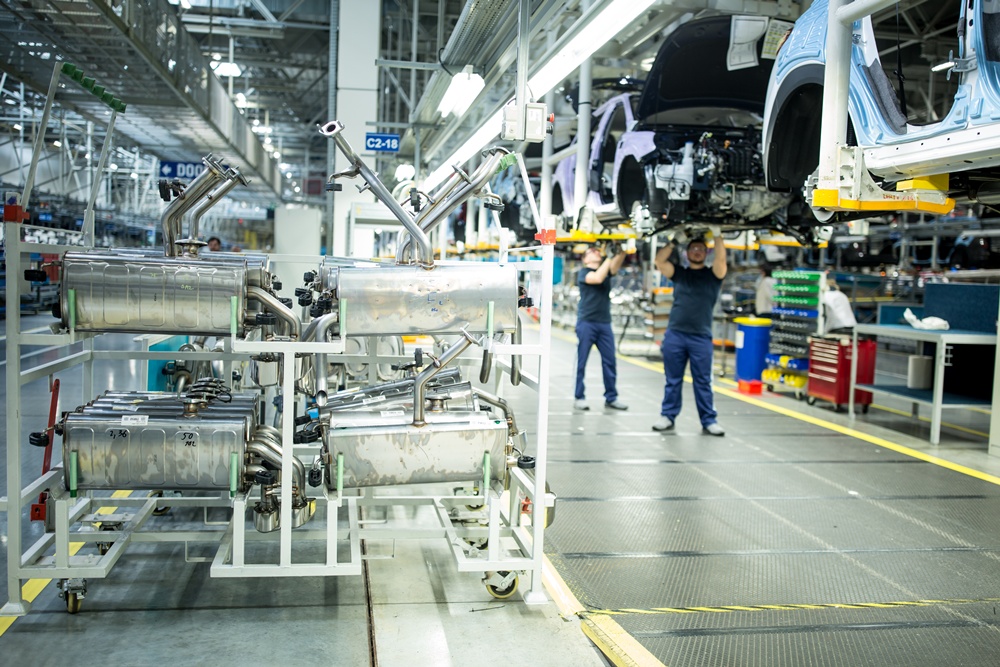 La foto muestra a unos trabajadores extranjeros ensamblando carros en una fábrica. | iClick Art (La reproducción o redistribución no autorizada de esta imagen está prohibida de acuerdo con las leyes de derechos de autor)