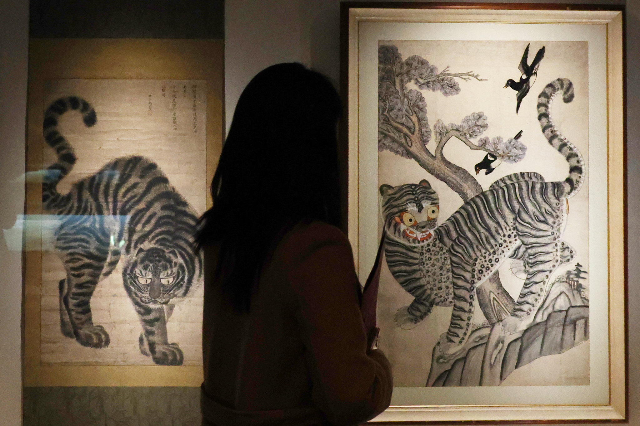 Una periodista observa una pintura popular hojakdo, que representa de manera humor&iacute;stica a un tigre y una urraca, el 25 de febrero en el sal&oacute;n de caligraf&iacute;a y pintura del Museo Nacional de Corea, en el distrito de Yongsan-gu, Se&uacute;l.