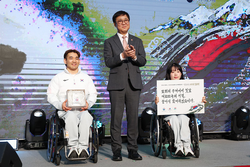 El 2 de febrero, el ministro de Cultura, Deportes y Turismo, Chae Hwi-young (centro), posa para una foto junto con uno de los integrantes del equipo de dobles mixtos de curling en silla de ruedas, Lee Yongsuk (izquierda), y la esquiadora nórdica Kim Yunji, durante la ceremonia de abanderamiento celebrada en el Olympic Parktel, en el distrito de Songpa-gu, en Seúl. | Lee Jeongwoo