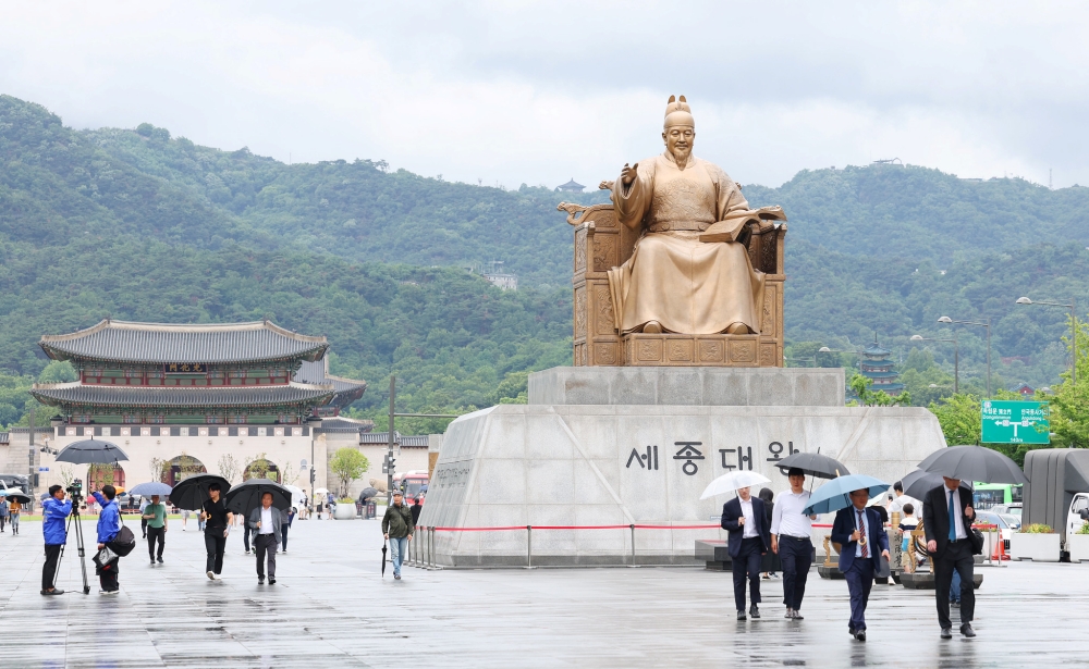  La foto muestra a los transe&uacute;ntes caminando cerca de la estatua del rey Sejong, en la plaza de Gwanghwamun, en Se&uacute;l. | Lee Jeong Woo