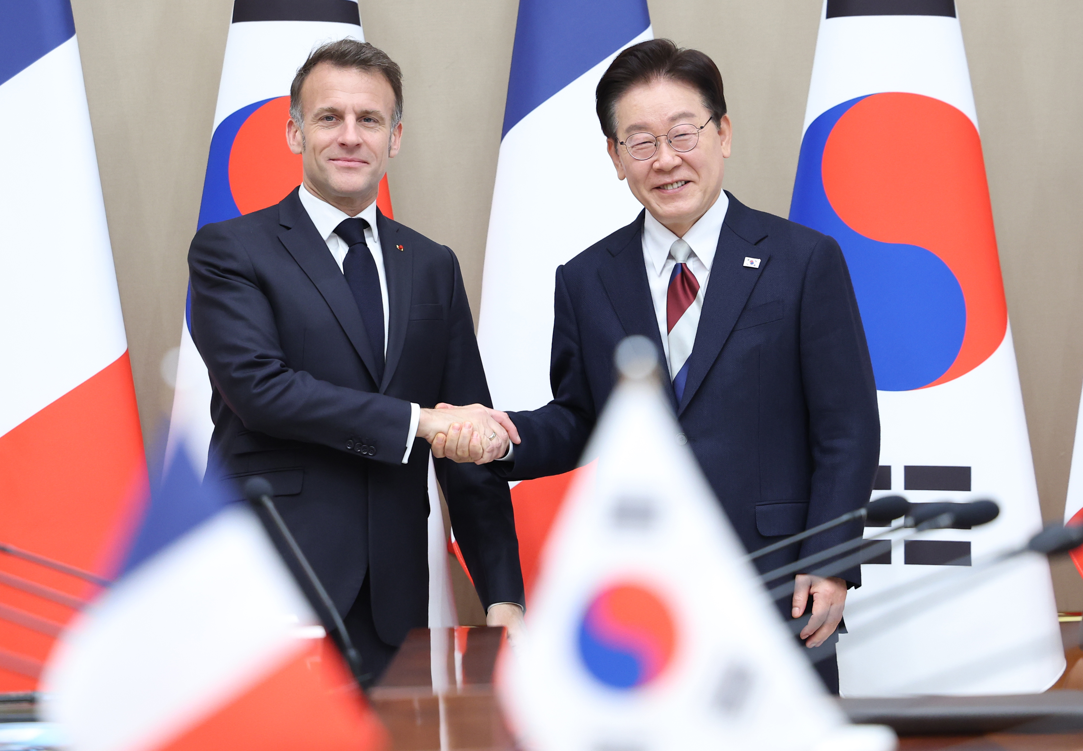  El presidente coreano, Lee Jae Myung (dcha.), estrecha la mano de su homólogo francés, Emmanuel Macron, durante la cumbre celebrada el 3 de abril, en la oficina presidencial de Cheong Wa Dae, en Seúl. | Agencia de Noticias Yonhap