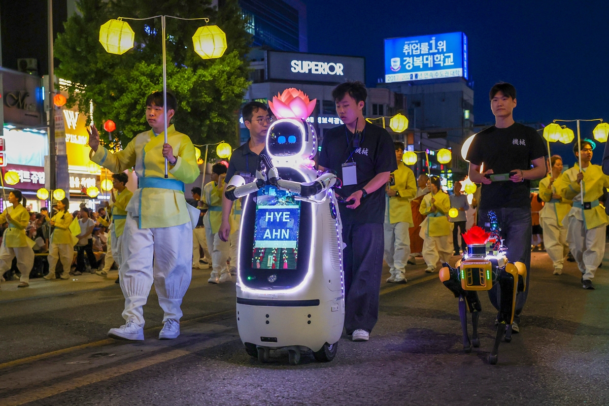 Hyean (izquierda) y Googi (derecha), un robot de patrulla y seguridad de cuatro patas equipado con m&uacute;ltiples sensores, encabezan el desfile de la Universidad Dongguk en el Festival de las Linternas de Loto, celebrado el 16 de mayo en el distrito de Jongno-gu, en Se&uacute;l, con motivo del D&iacute;a del Nacimiento de Buda, el 25 de mayo.