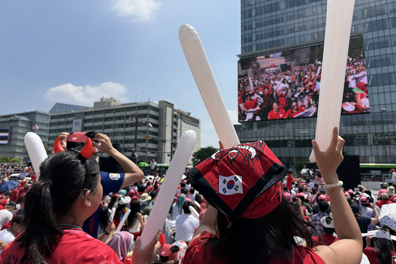El 12 de junio, los 'Diablos Rojos', la icónica hinchada oficial de la selección nacional de fútbol de Corea, lanzan vítores para apoyar al equipo mientras se transmite el partido en vivo en pantallas gigantes en la plaza de Gwanghwamun, en el distrito de Jongno-gu, Seúl. | Angie Hon