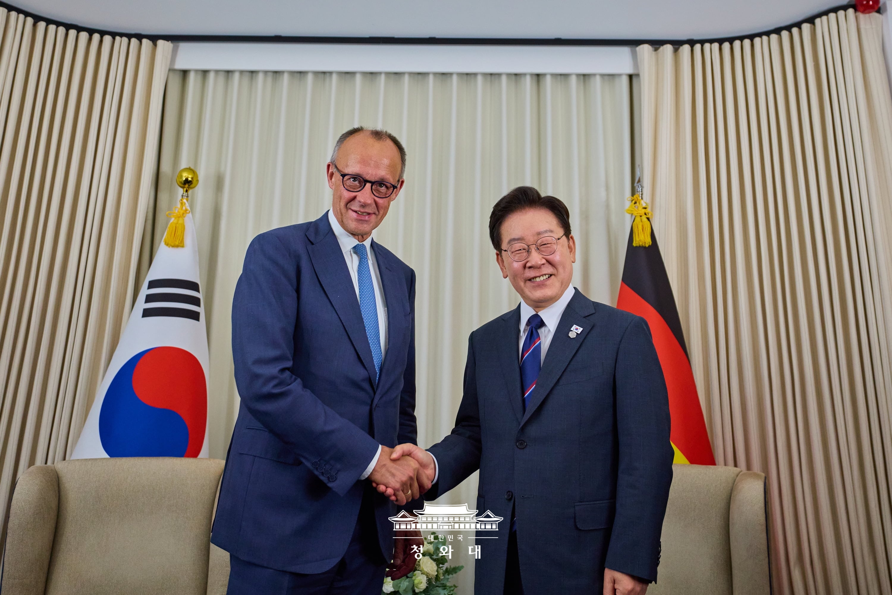 El presidente coreano, Lee Jae Myung, y el canciller alem&aacute;n Friedrich Merz se dan un apret&oacute;n de manos tras su reuni&oacute;n bilateral el 16 de junio (hora local) en &Eacute;vian-les-Bains, Francia, sede de la cumbre del G7.