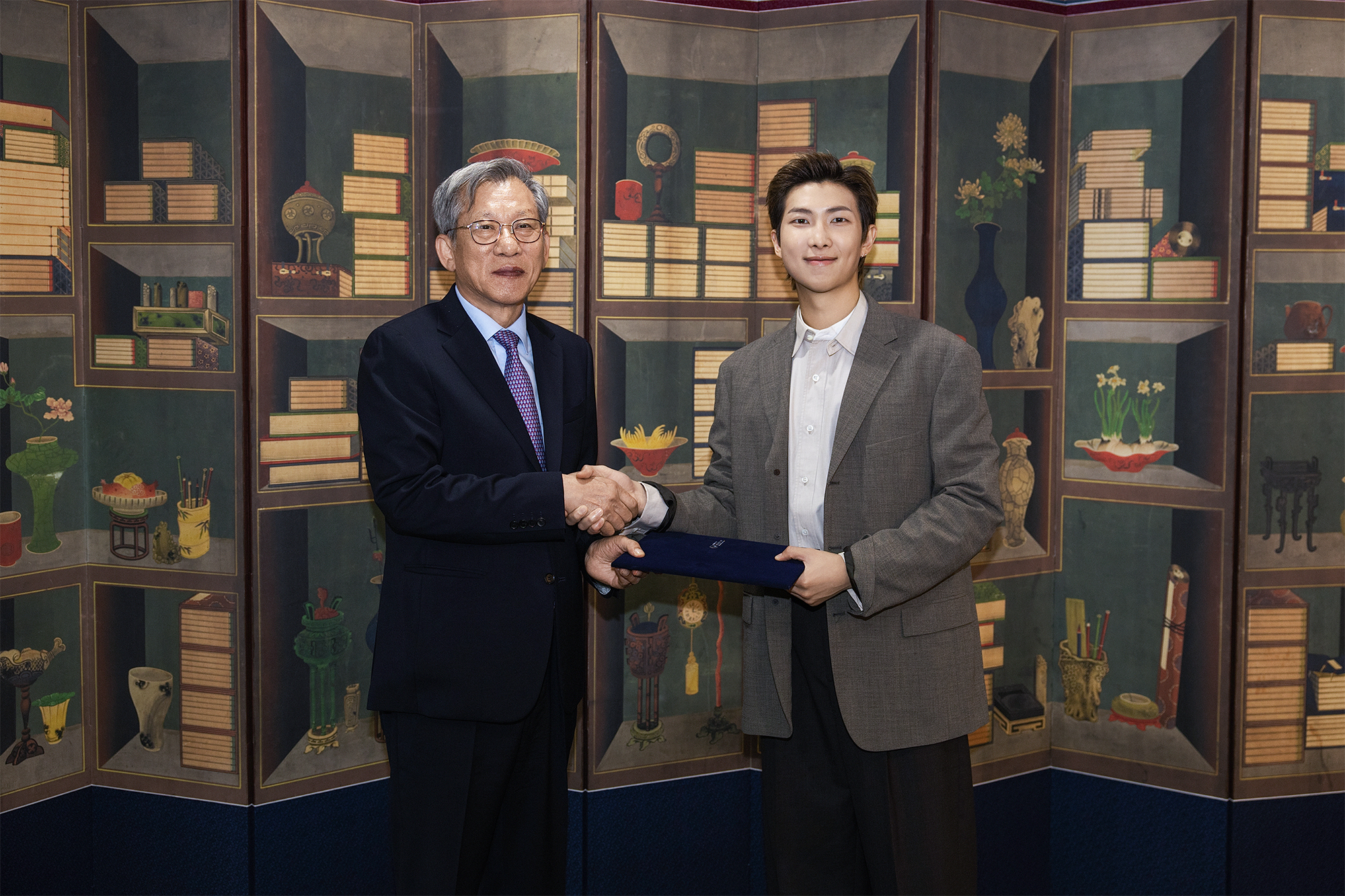 RM (derecha), l&iacute;der del supergrupo de K-pop BTS, y You Hong-june, director del Museo Nacional de Corea, se dan un apret&oacute;n de manos tras el nombramiento del artista como embajador global del museo, el 19 de junio en Se&uacute;l. | Museo Nacional de Corea