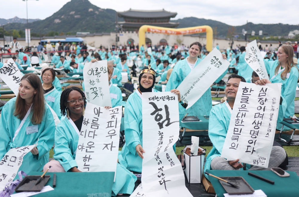 Unos participantes extranjeros muestran sus escritos a mano, durante el ‘Concurso de Caligrafía Conmemorativo del 579º Aniversario de la Creación del Hangeul’, celebrado el 9 de octubre de 2025, en la plaza Gwanghwamun, en Seúl. | Agencia de Noticias Yonhap