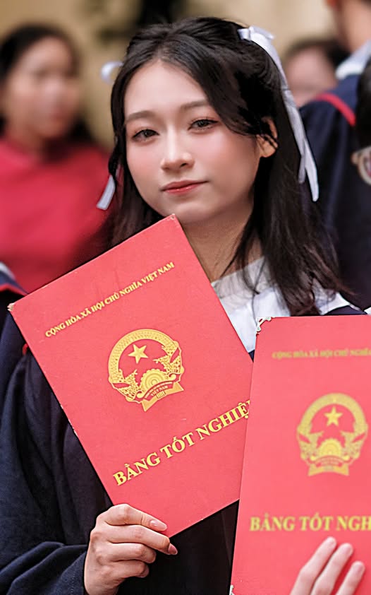 Hoang Huong Giang posa sosteniendo su diploma durante la ceremonia de graduación.