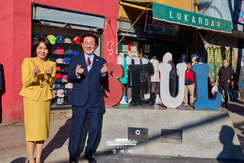 El presidente Lee Jae Myung (dcha.) y la primera dama Kim Hea Kyung posan haciendo un coraz&oacute;n con los dedos, mientras les tomaban una foto, durante su visita a la calle 'Se&uacute;l,  en el barrio Patronato en la comuna de Recoleta, en Santiago de Chile, el 30 de julio (hora local). La pareja visit&oacute; el sector de Patronato &mdash;donde se concentra la mayor cantidad de comercios coreanos&mdash; para brindar su apoyo a los comerciantes y dar continuidad a sus encuentros con la comunidad residente en el extranjero.