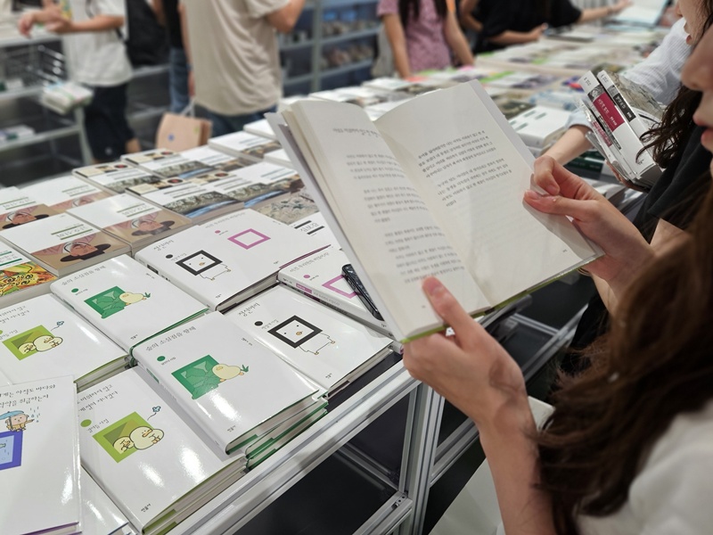 Una visitante examina un poemario de la editorial Minumsa ilustrado con personajes coreanos,  el 23 de agosto, en la tienda temporal 'Minumsa x Cutie Today: El mundo m&aacute;s all&aacute; de las frases', instalada en el centro comercial I'Park Mall de Yongsan, en Se&uacute;l. | Lee Ji Yae