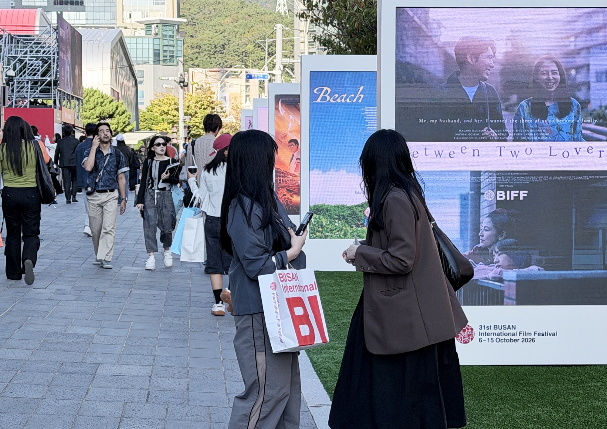 Varios transe&uacute;ntes observan las pantallas electr&oacute;nicas con la programaci&oacute;n de la 31&ordf; edici&oacute;n del Festival Internacional de Cine de Busan (BIFF, por sus siglas en ingl&eacute;s), en el Centro de Cine de Busan, en el distrito de Haeundae-gu, el 7 de octubre. | Xu Aiying