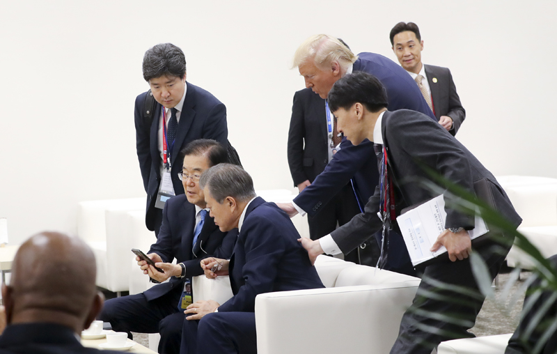 El presidente estadounidense, Donald Trump se acerca al presidente Moon Jae-in el 29 de junio en el centro de convenciones INTEX Osaka para preguntar si ha leído su tweet sobre la posbilidad de ver al líder norcoreano Kim Jong Un en la frontera intercoreana, mientras el representante surcoreano conversa con el director de Oficina de Seguridad Nacional, Chung Eui-Yong. | Yonhap News