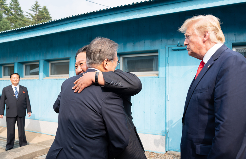 El presidente Moon y su par norcoreano Kim se abrazan en la Línea de Demarcación Militar en Panmunjeom mientras el presidente Trump los está mirando. | La Casa Blanca