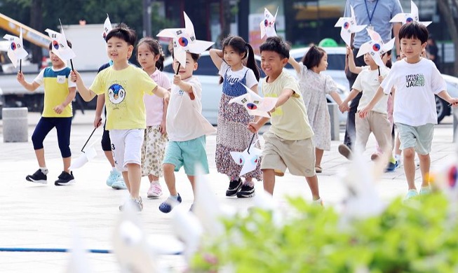 En vísperas del Día de la Liberación unos niños agitan los molinetes patrióticos de la bandera surcoreana