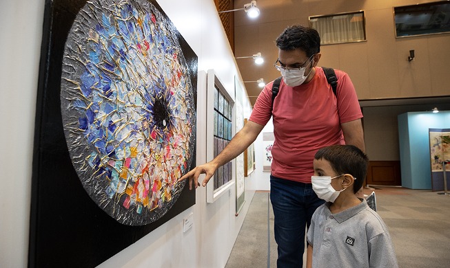 Padre e hijo admiran obras de exposición de artistas con discapacidad