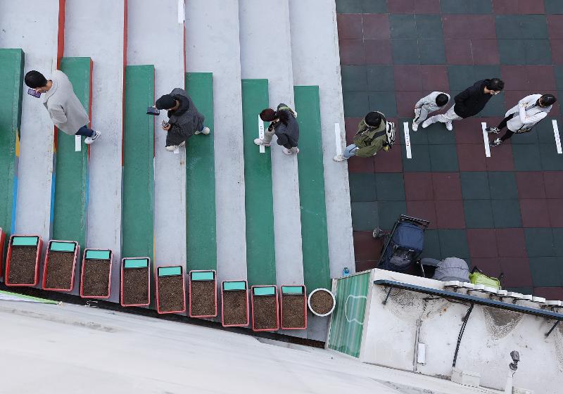 Los ciudadanos mantienen el distanciamiento social mientras esperan para emitir su voto en las 21º elecciones legislativas el 10 de abril, el primer día de la votación anticipada, en un colegio electoral en el distrito de Seongdong-gu en Seúl. 